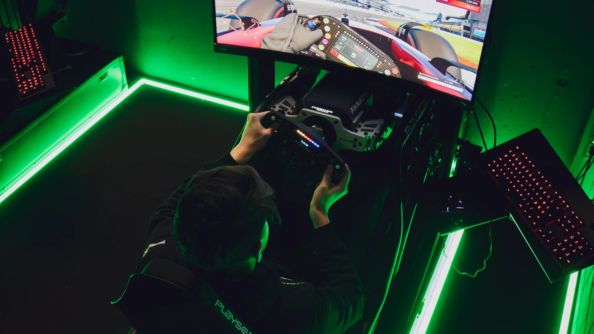 Esports gaming station with neon green LED lighting, a large screen displaying gameplay, and an immersive setup.