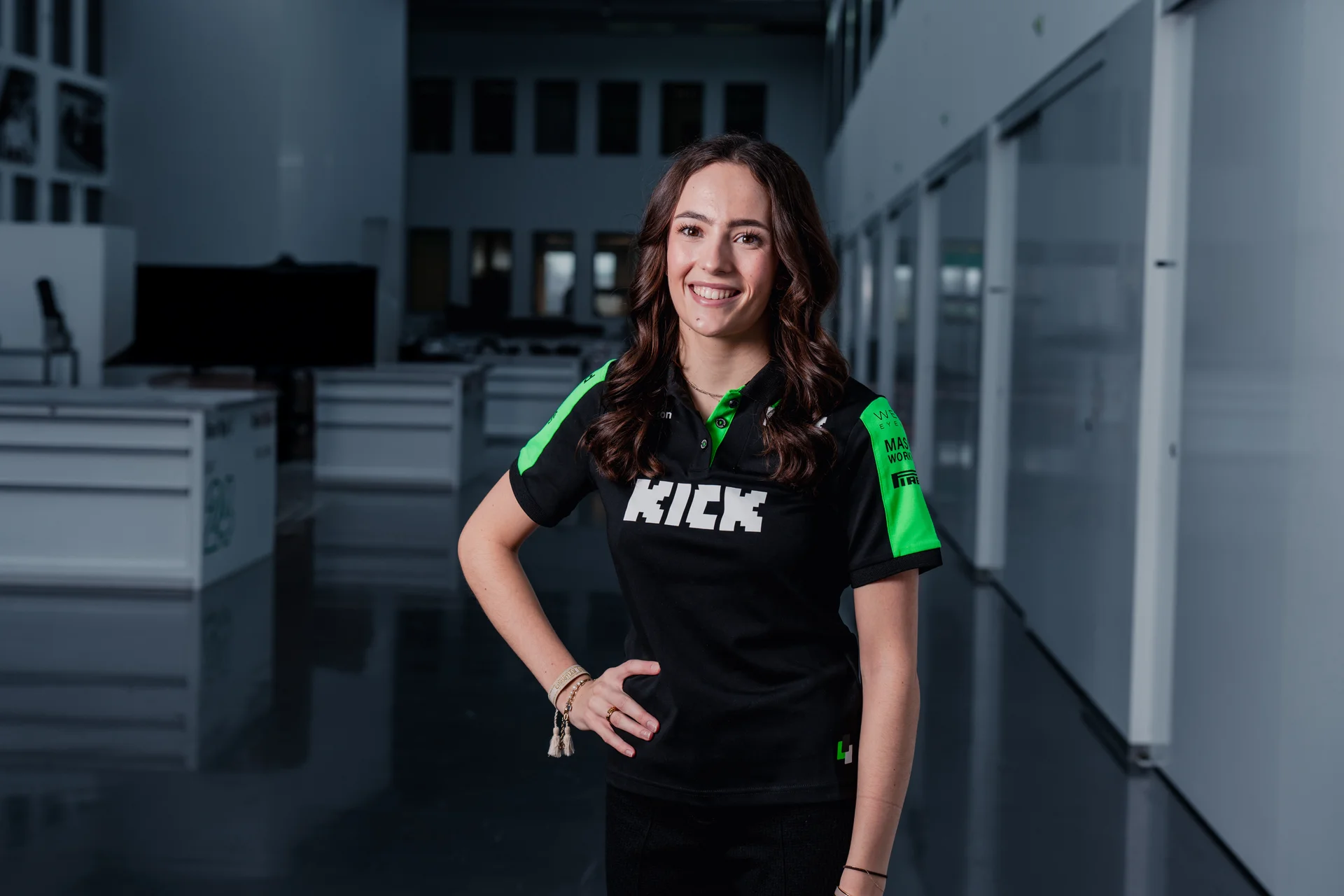 Carrie Schreiner, professional racing driver, wearing Sauber Motorsport team apparel, posing in a modern indoor setting after being announced as the team’s brand ambassador.