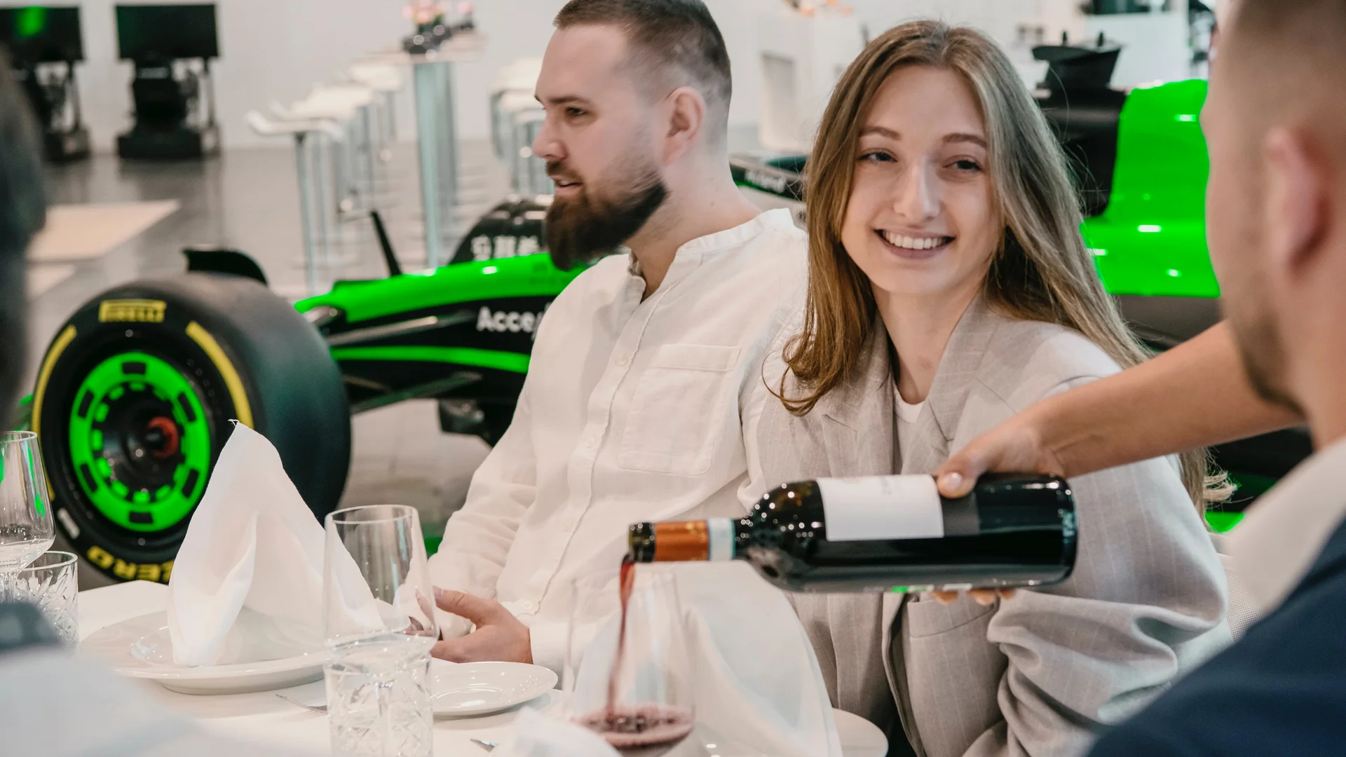 Guests enjoying a luxurious dining experience at a Sauber Group event in Hinwil, with a Formula 1 car visible in the background.