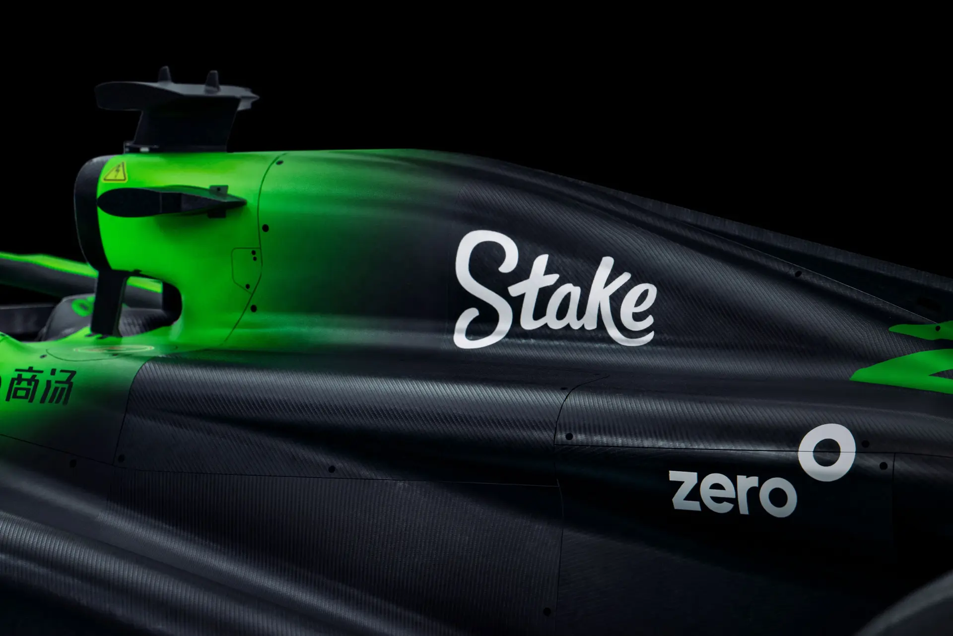 Close-up side view of the Sauber C45 Formula 1 car, highlighting the Stake branding and aerodynamic design on the right sidepod. The car's glossy green and black livery is visible under dramatic lighting.