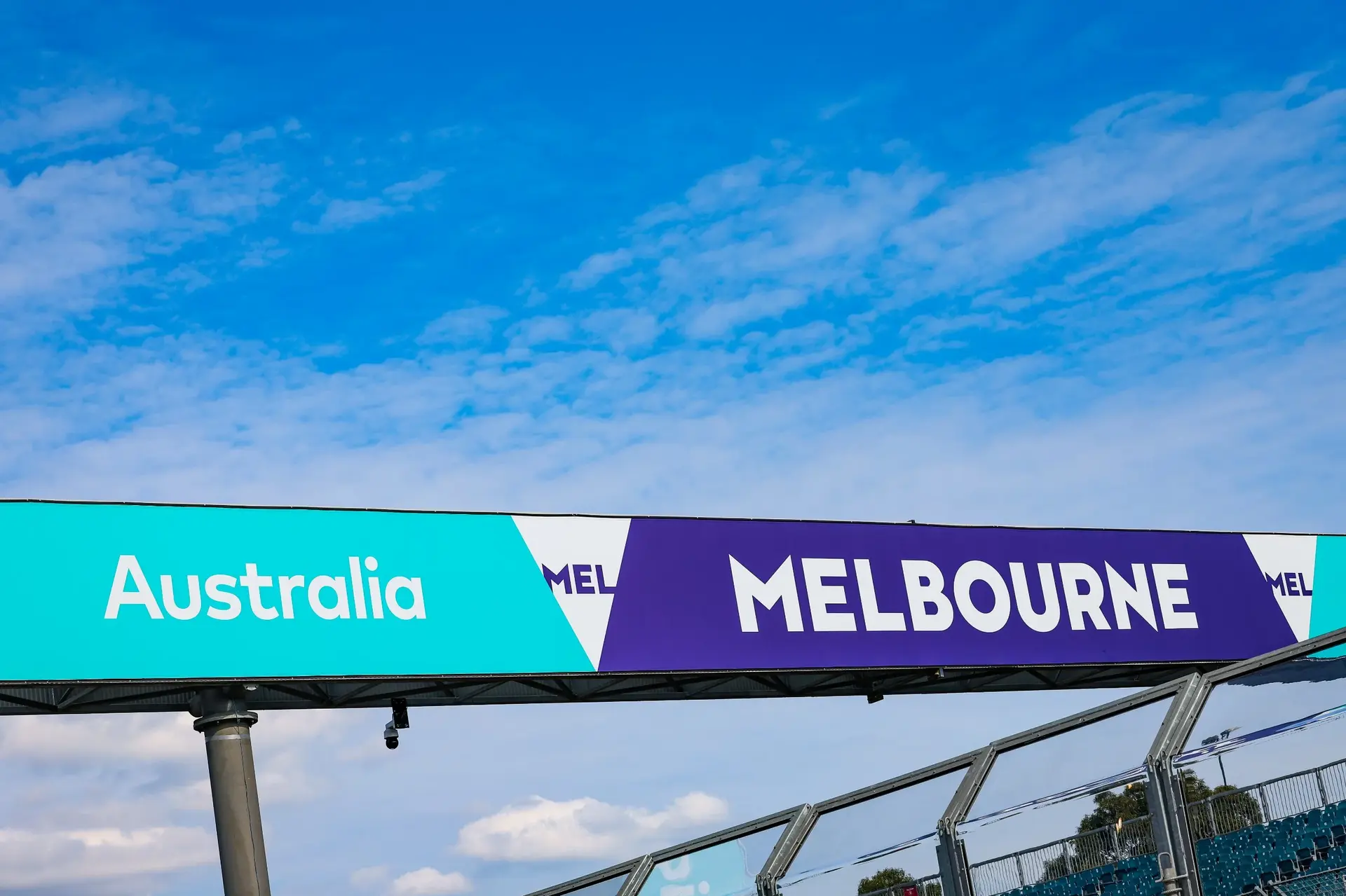 Melbourne Grand Prix Circuit sign at Albert Park, showcasing the official branding for the Australian Grand Prix 2025 under a blue sky with scattered clouds.