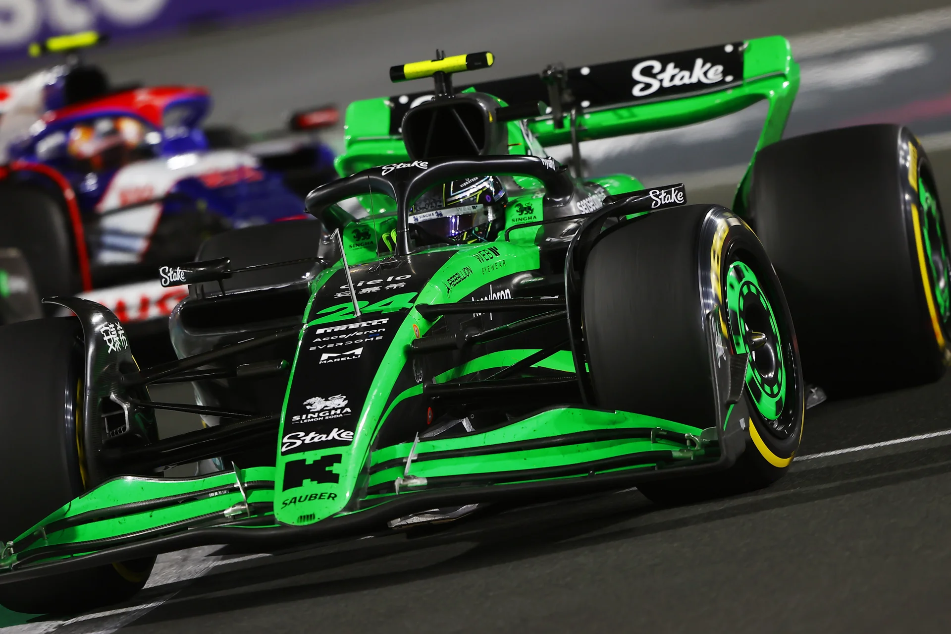 A green and black Formula 1 car racing on the track at the 2024 Saudi Arabian Grand Prix under bright lights, with another car closely behind.