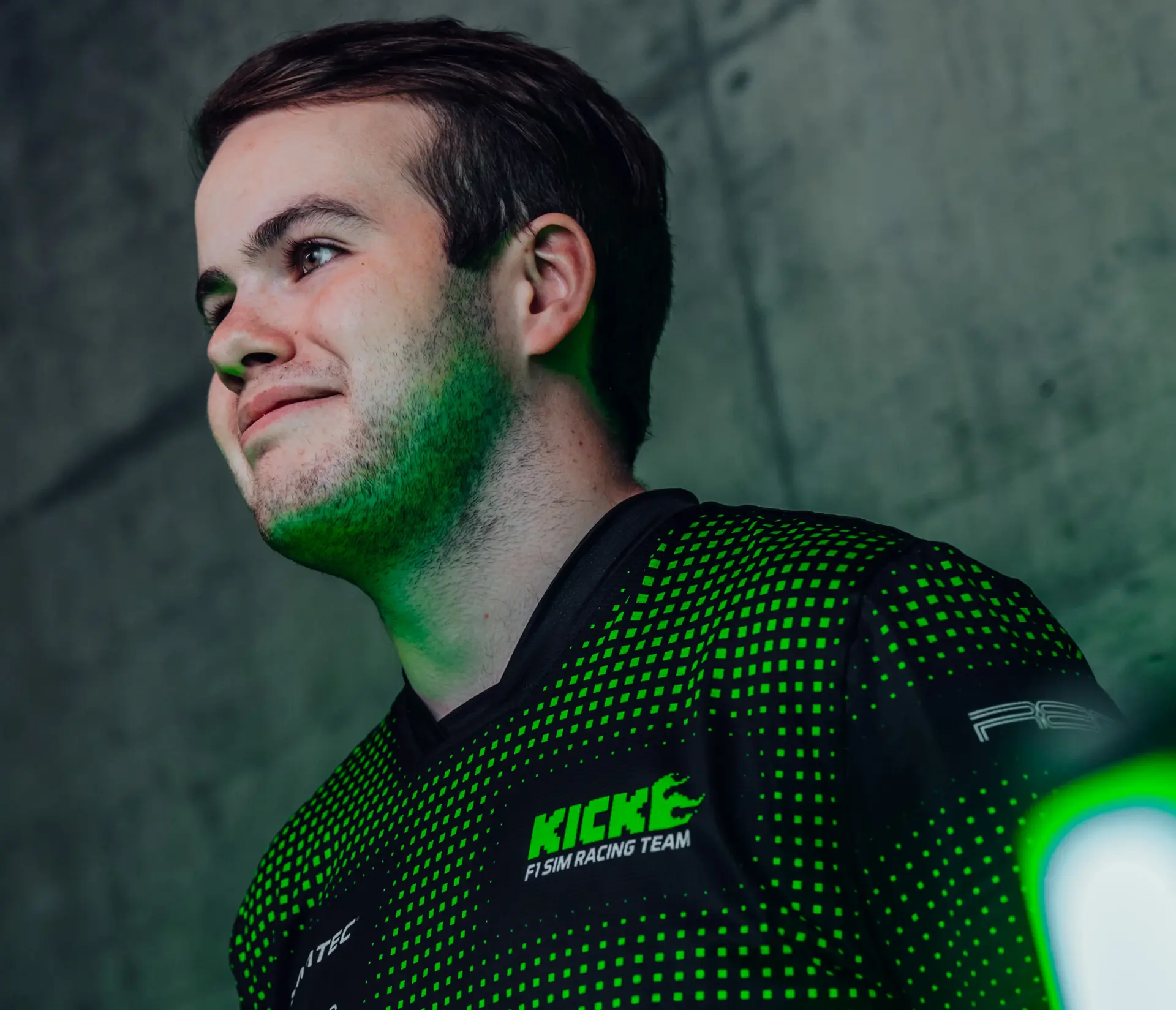 Thomas Ronhaar, Sauber Motorsport Esports driver, in a neon-lit gaming environment, wearing a racing team jersey.