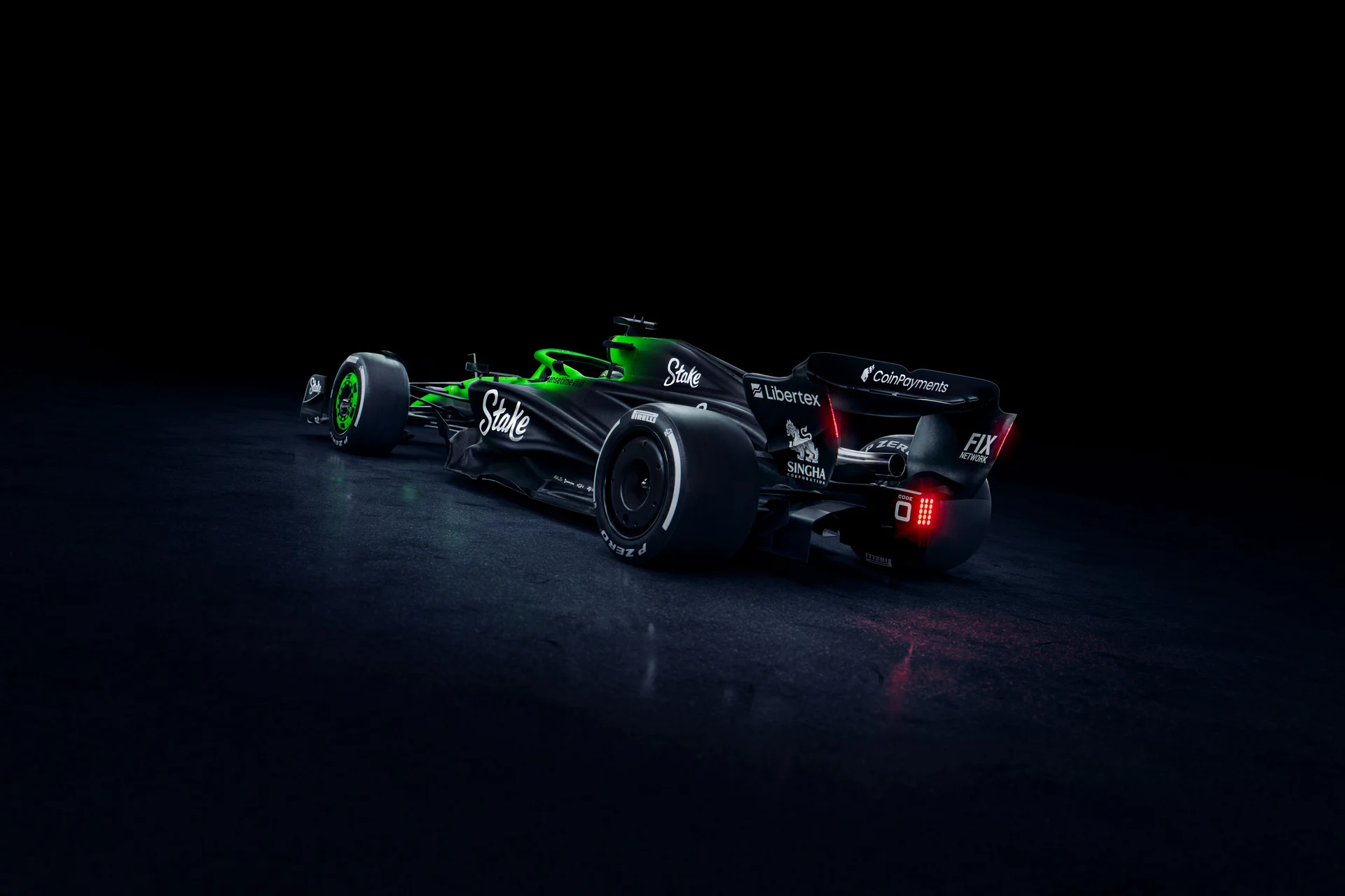 Rear three-quarter view of the Sauber C45 Formula 1 car, highlighting the Stake sponsorship and intricate aerodynamic design. The illuminated green and black livery contrasts against a dark background, showcasing the rear wing and diffuser.