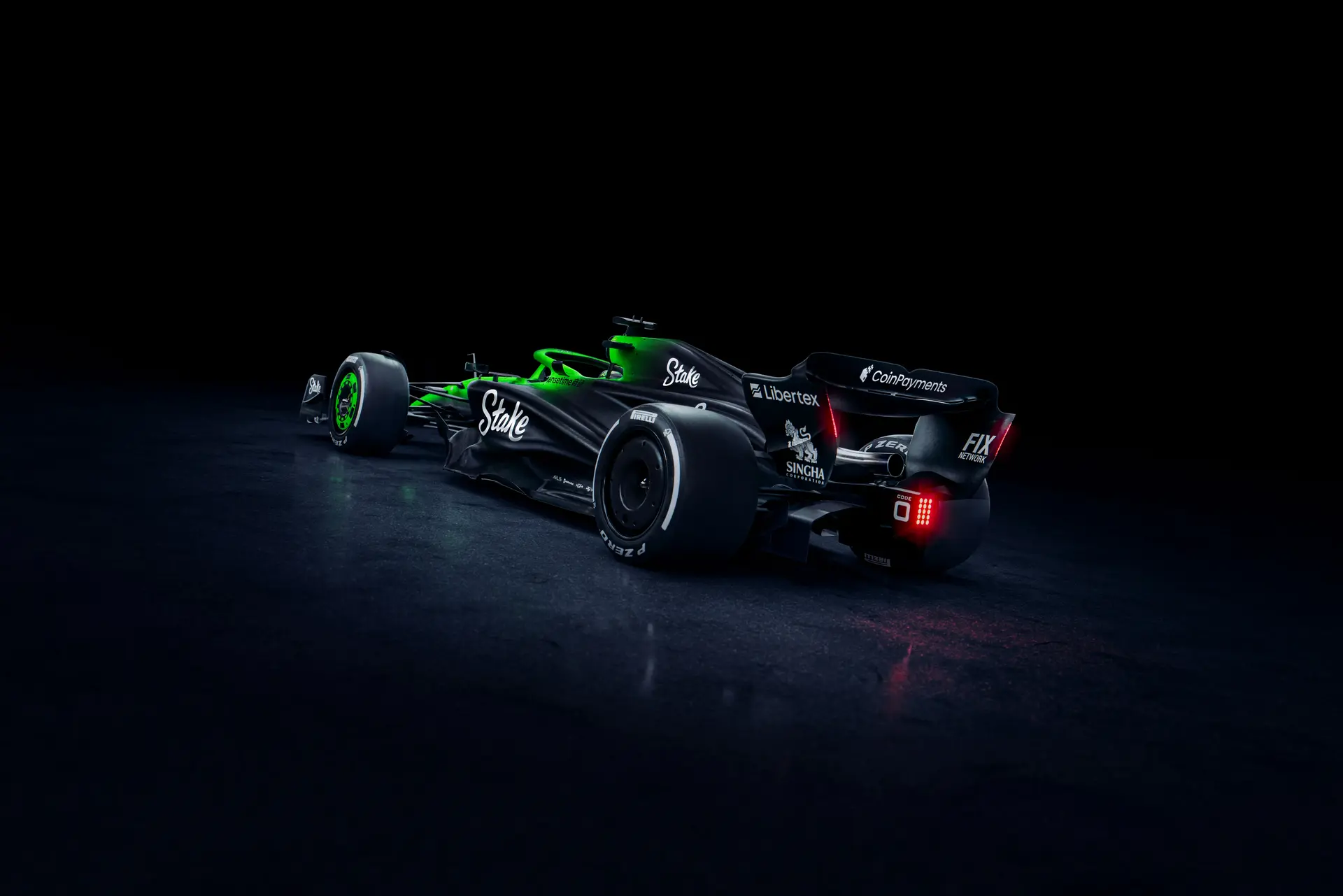 Rear three-quarter view of the Sauber C45 Formula 1 car, highlighting the Stake sponsorship and intricate aerodynamic design. The illuminated green and black livery contrasts against a dark background, showcasing the rear wing and diffuser.
