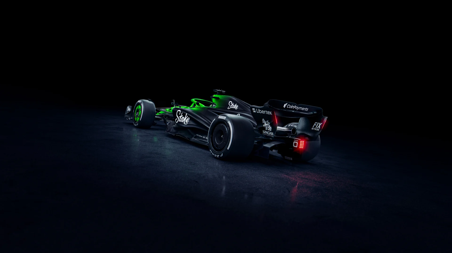 Rear three-quarter view of the Sauber C45 Formula 1 car, highlighting the Stake sponsorship and intricate aerodynamic design. The illuminated green and black livery contrasts against a dark background, showcasing the rear wing and diffuser.