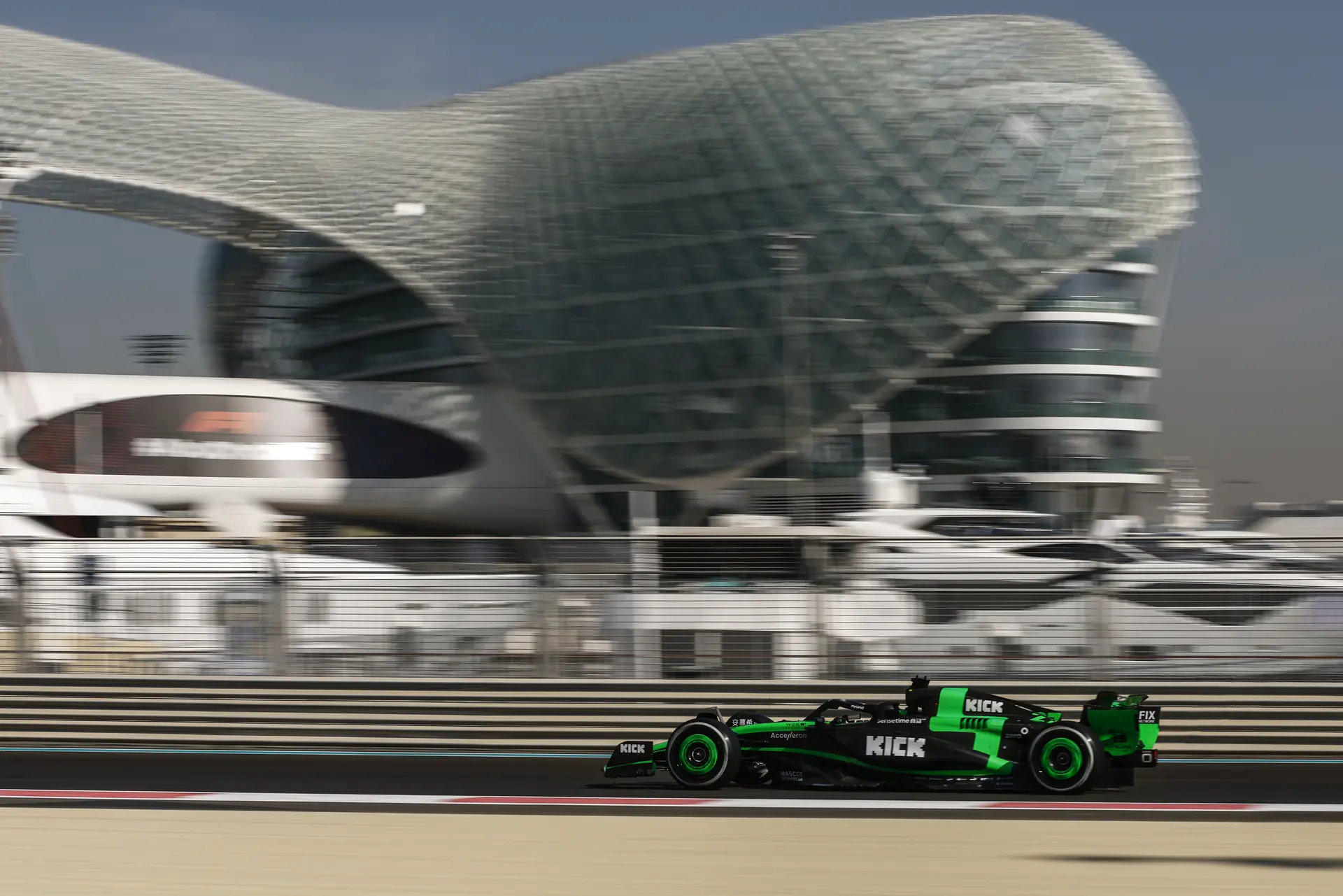 Sauber F1 car on track during the 2024 Abu Dhabi post-season test at Yas Marina Circuit, with the futuristic architecture of the W Hotel in the background.