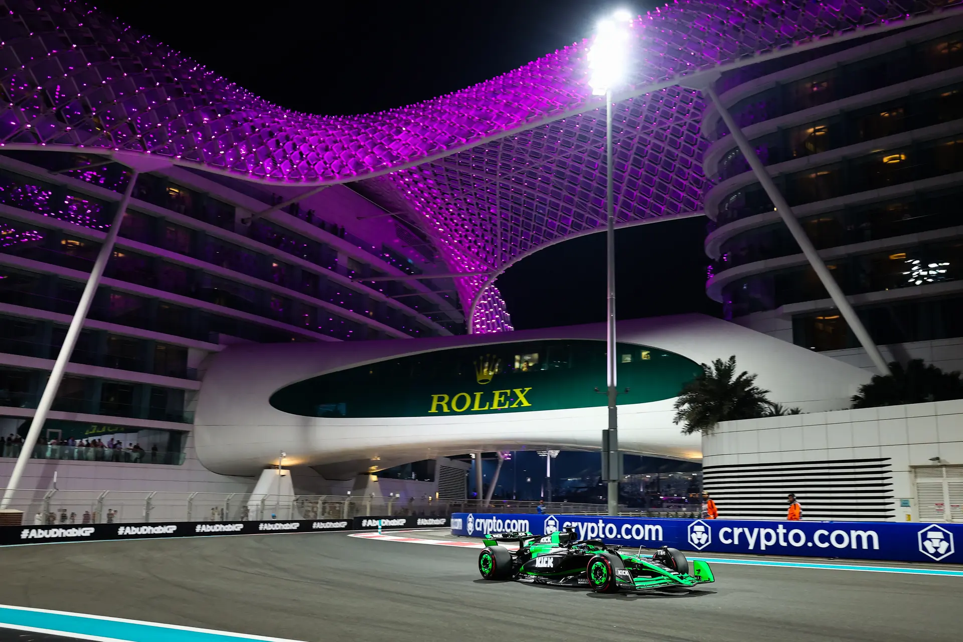 A stunning night view of Yas Marina Circuit during the 2024 Abu Dhabi Grand Prix, with vibrant purple lights illuminating the grandstands and the track below.