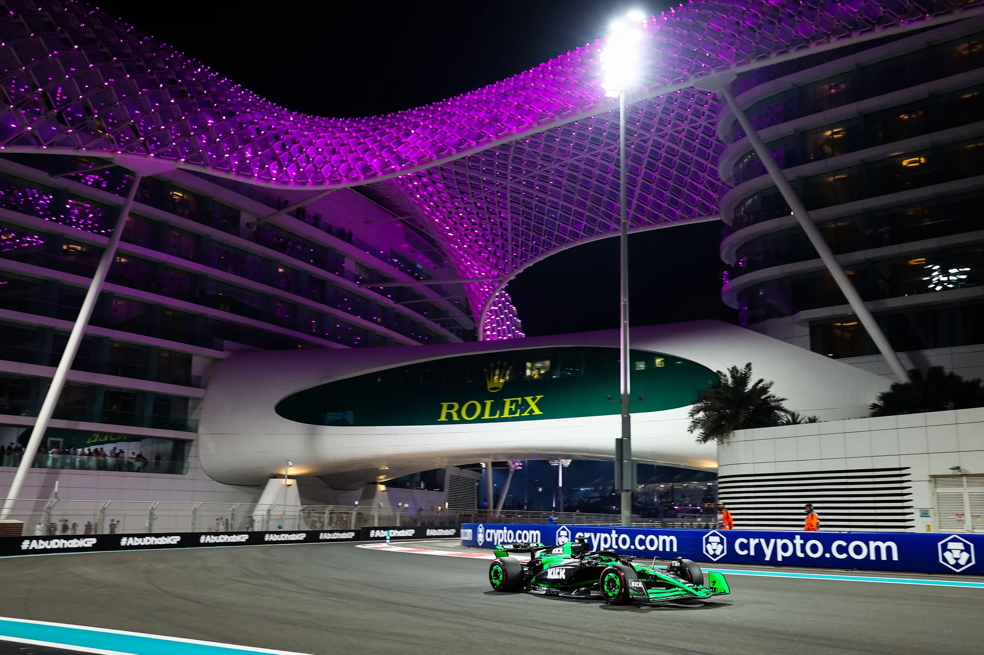 A stunning night view of Yas Marina Circuit during the 2024 Abu Dhabi Grand Prix, with vibrant purple lights illuminating the grandstands and the track below.
