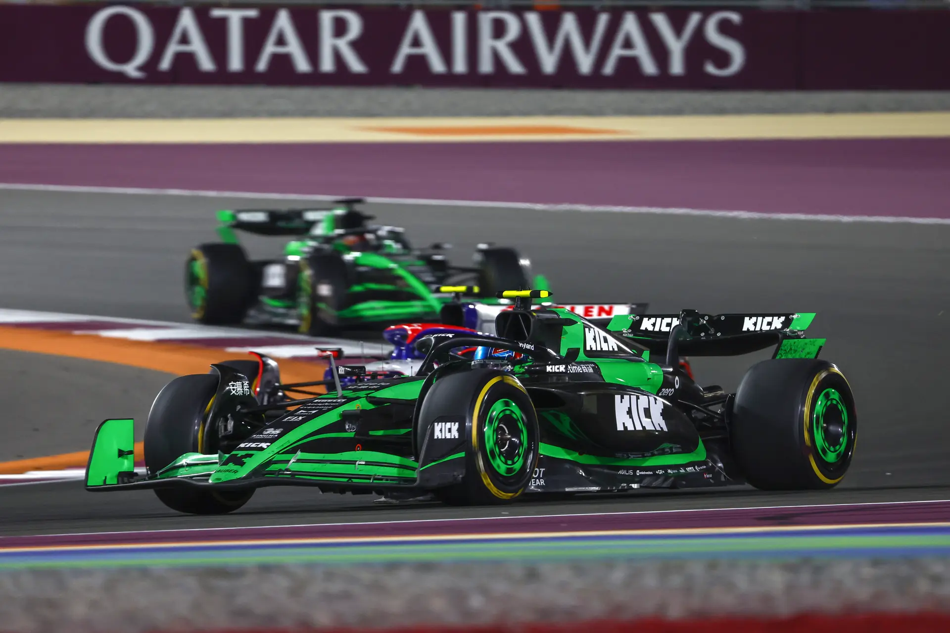 A Sauber F1 car in action during the 2024 Qatar Grand Prix race, speeding under the floodlights with Qatar Airways branding in the background.