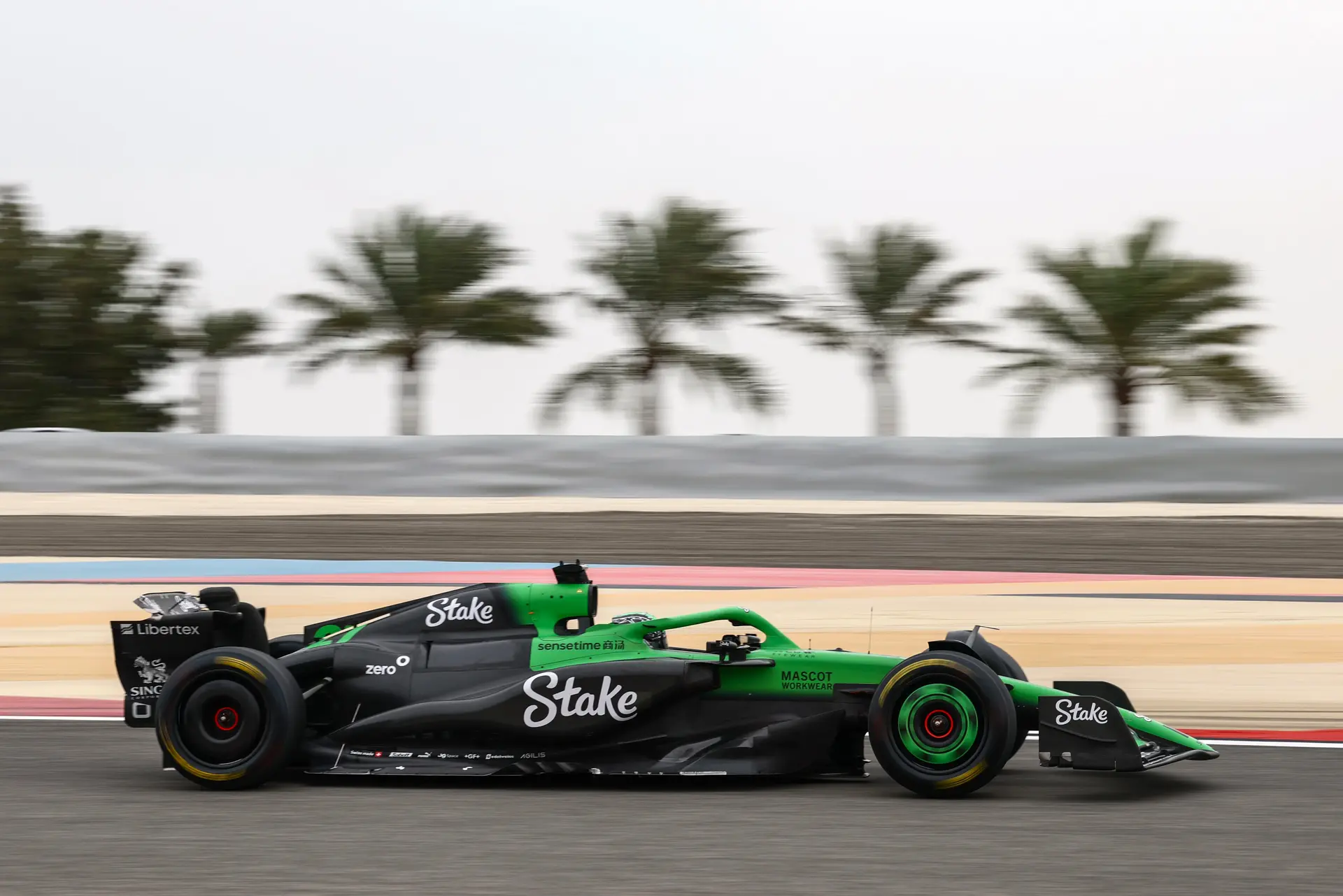 A Sauber F1 car on track during the 2025 pre-season testing, showcasing high-speed performance and aerodynamic design against a backdrop of palm trees.