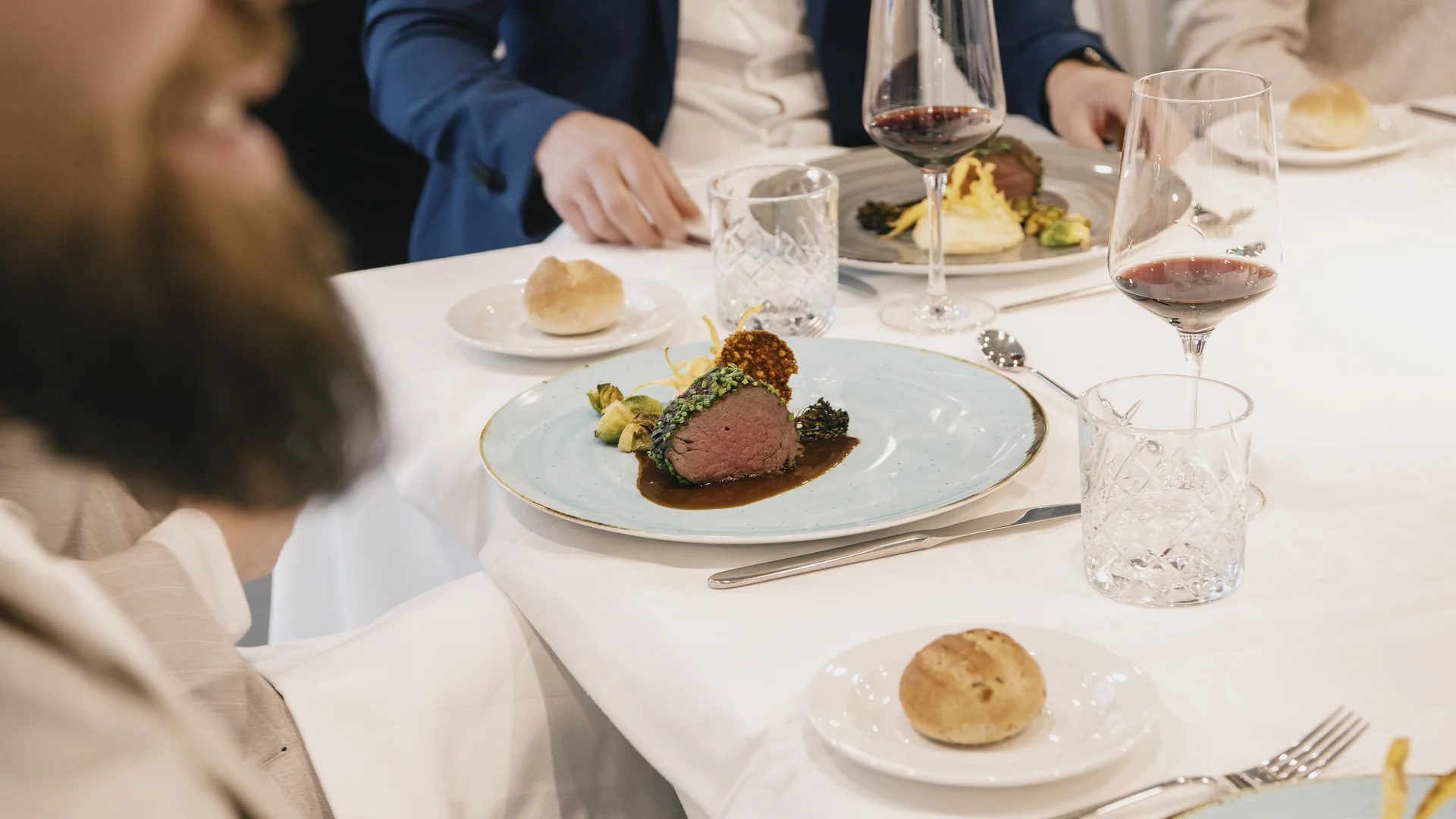 Guests enjoying a fine dining experience at a Sauber Group event in Hinwil, with elegantly plated gourmet dishes and wine.