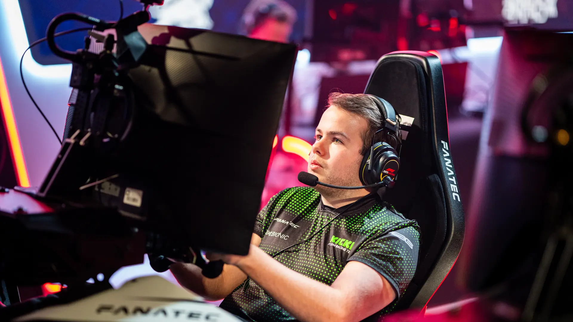 Thomas Ronhaar, Sauber Motorsport Esports driver, intensely focused while competing in an F1 sim racing event, illuminated by a vibrant gaming setup.