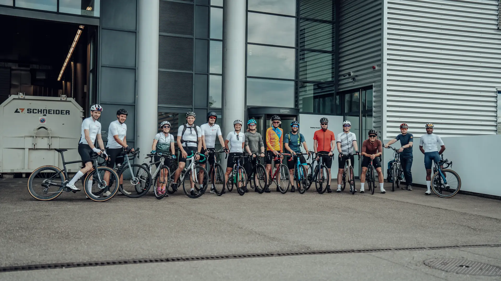 Group of Sauber Motorsport employees and cycling enthusiasts gathered for an industrial building for an afterwork cycling event.