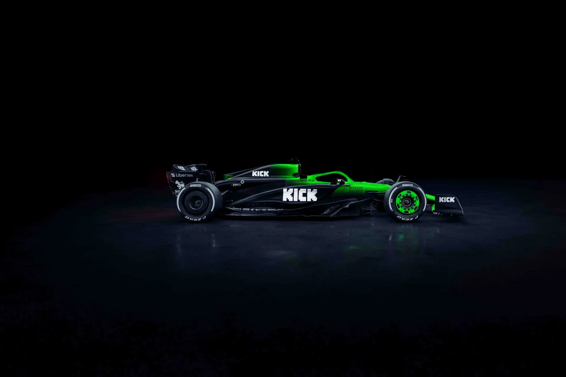 Side view of the Sauber C45 Formula 1 car from the right, showcasing its aerodynamic profile, green and black livery, and sponsor logos in a dark setting.