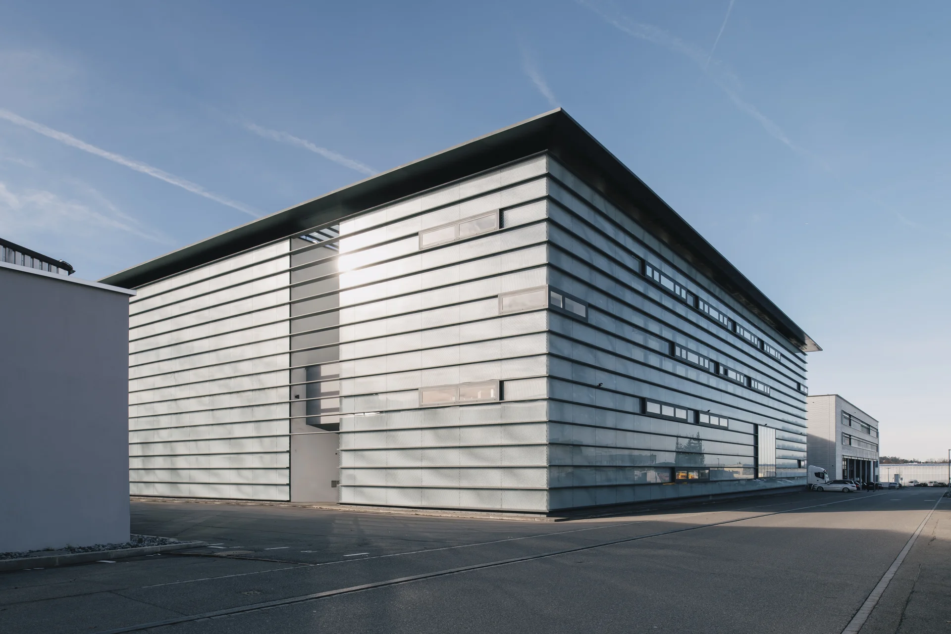 Exterior view of the Sauber F1 Team headquarters in Hinwil, Switzerland, showcasing its modern architectural design under a clear blue sky.