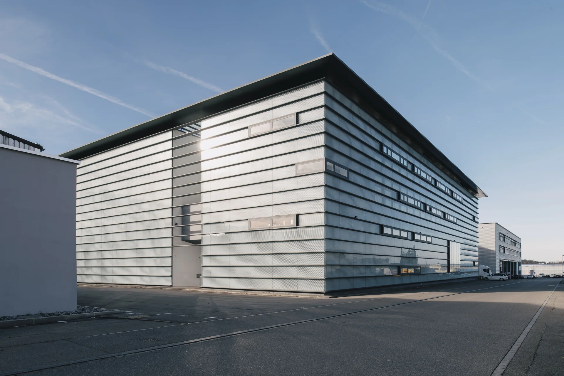 Exterior view of the Sauber F1 Team headquarters in Hinwil, Switzerland, showcasing its modern architectural design under a clear blue sky.